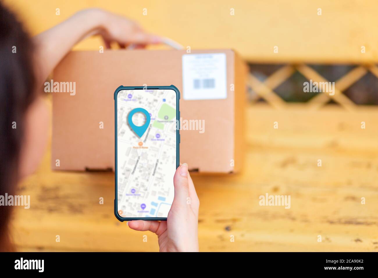 Una donna esegue la scansione del codice pacco utilizzando il suo smartphone. Mappa online sul cellulare. Concetto di corriere e tecnologie moderne. Foto Stock