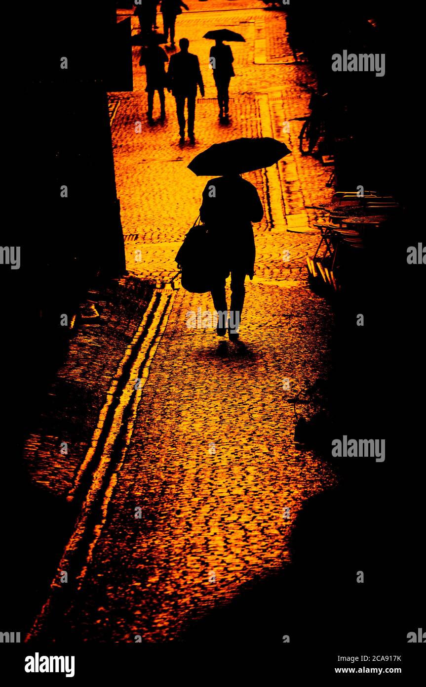Donna con umbrealla in un vicolo acciottolato Foto Stock
