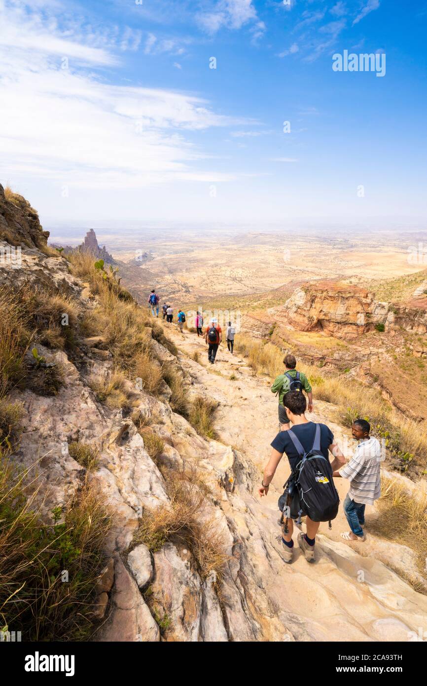 Gli escursionisti si avventurano su un sentiero roccioso verso le chiese scavate nella roccia dei monti Gheralta, della regione del Tigray, dell'Etiopia, dell'Africa Foto Stock