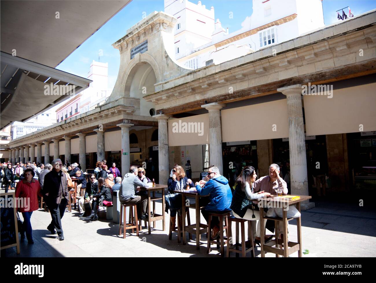 I visitatori del mercato alimentare di Cadice mangiano su tavoli e sgabelli all'aperto Foto Stock