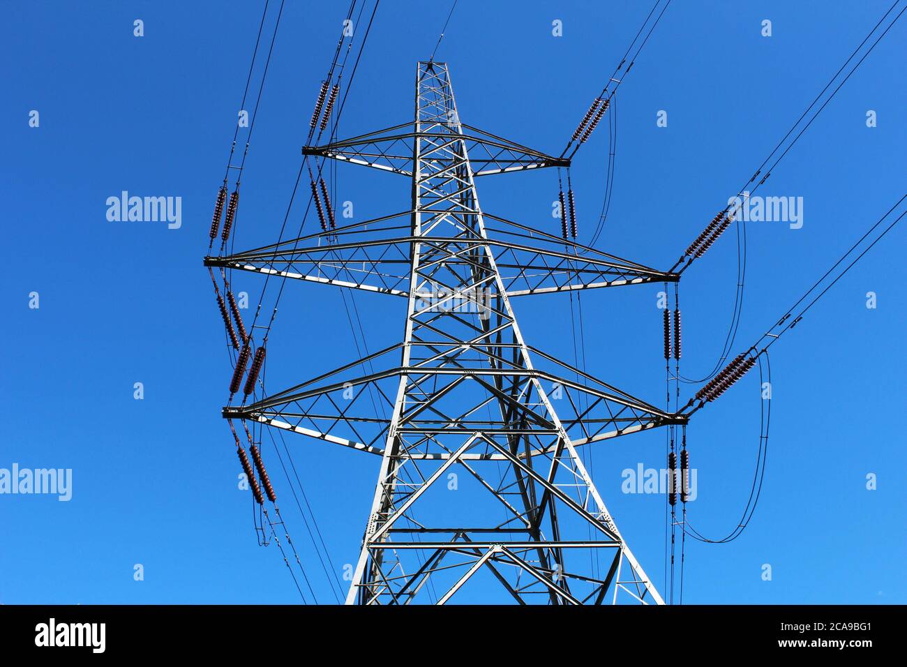 Grande, pilone elettrico in metallo (torre di trasmissione) vista dal suolo con cielo blu a Manchester, Inghilterra Foto Stock