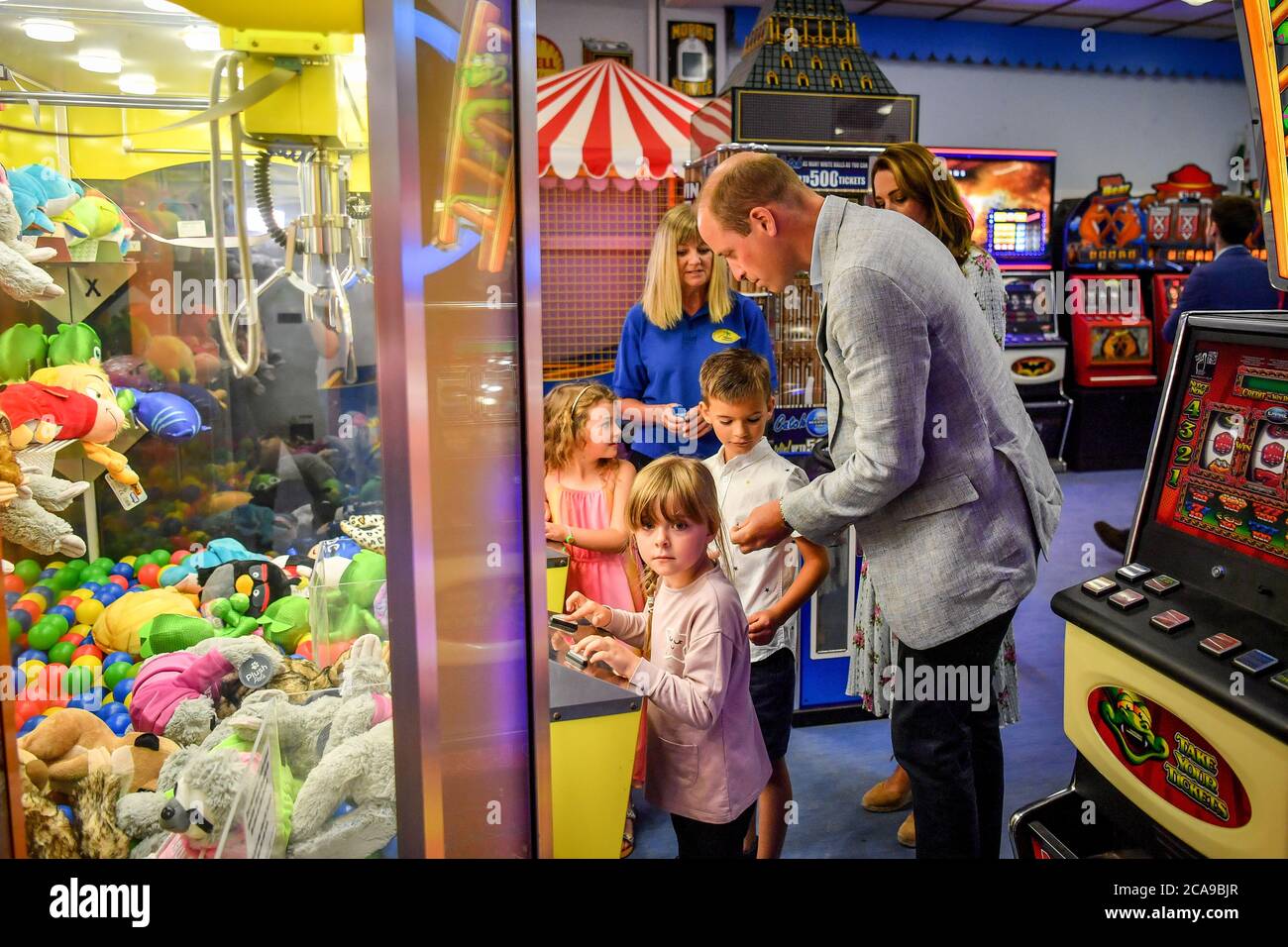 Il duca di Cambridge consegna una moneta a Jamie Case, 7, così lui e il suo amico, Erin Phillips, 5, (a sinistra) e la sorella Hollie Case, 5, (davanti) possono giocare su una macchina per il gioco del tè presso l'Island Leisure Amusement Arcade, dove Gavin e Stacey sono girati, durante la loro visita a Barry Island, Galles del Sud, per parlare con gli imprenditori locali circa l'impatto di COVID-19 sul settore turistico. Foto Stock