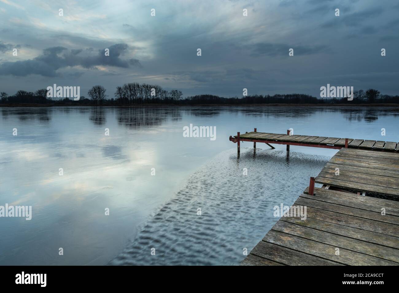 Un molo in legno su un lago ghiacciato e un cielo serale Foto Stock