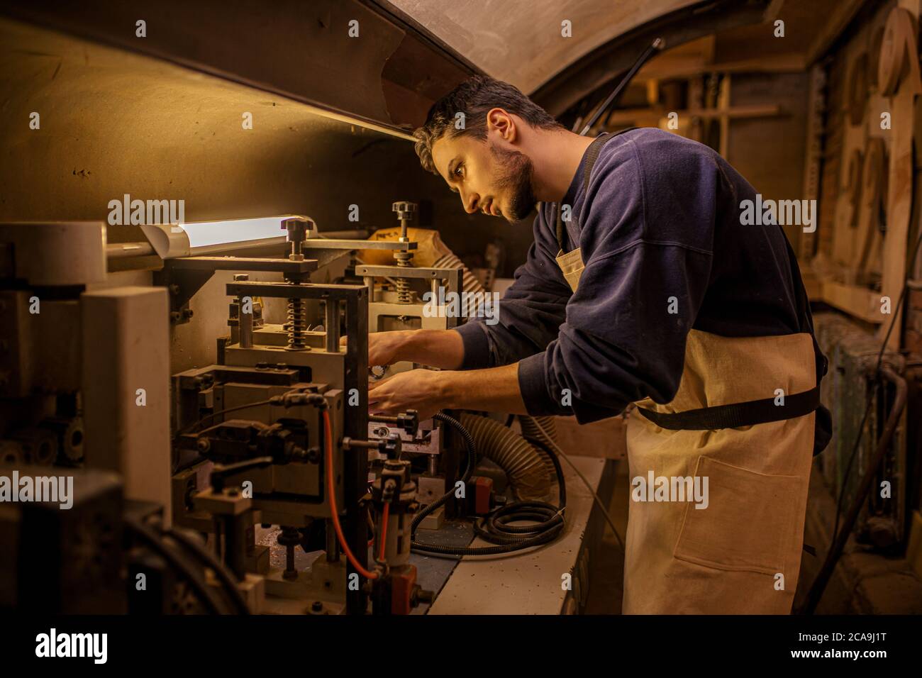 sicuro lavoratore di legno caucasico o falegname che si occupa di macchina elettrica al banco da lavoro. produttore di mobili che lavora da solo in fabbrica Foto Stock