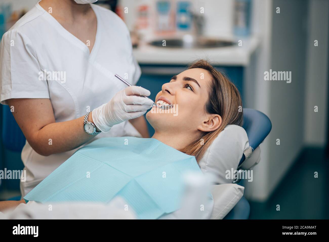 dentista professionista attento in uniforme bianca trattando i denti del paziente, facendo sorriso perfetto per i pazienti, utilizzando apparecchiature mediche Foto Stock