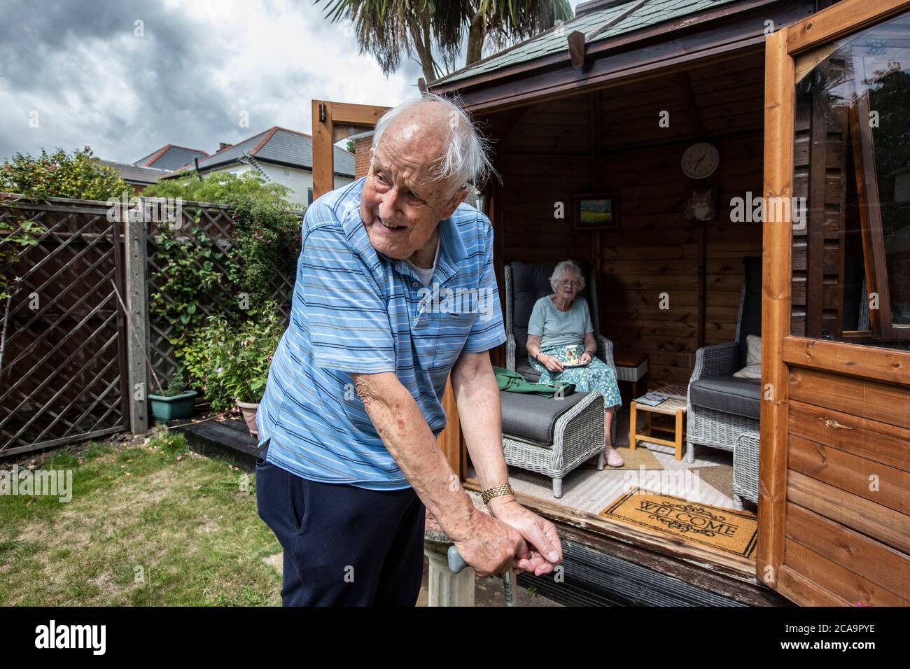 Coppie anziane negli anni 80 che si godono il caldo clima estivo nella loro casa estiva giardino, Inghilterra, Regno Unito Foto Stock