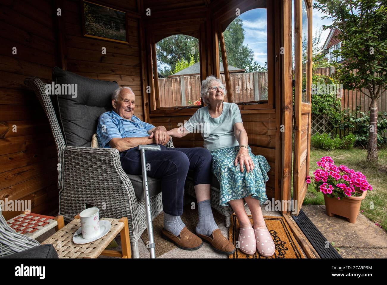 Coppie anziane negli anni 80 che si godono il caldo clima estivo nella loro casa estiva giardino, Inghilterra, Regno Unito Foto Stock