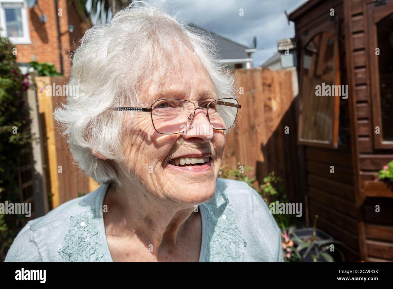 Donna anziana nei suoi anni '80 che svolge attività di giardinaggio nel suo giardino residenziale posteriore, Inghilterra, Regno Unito Foto Stock