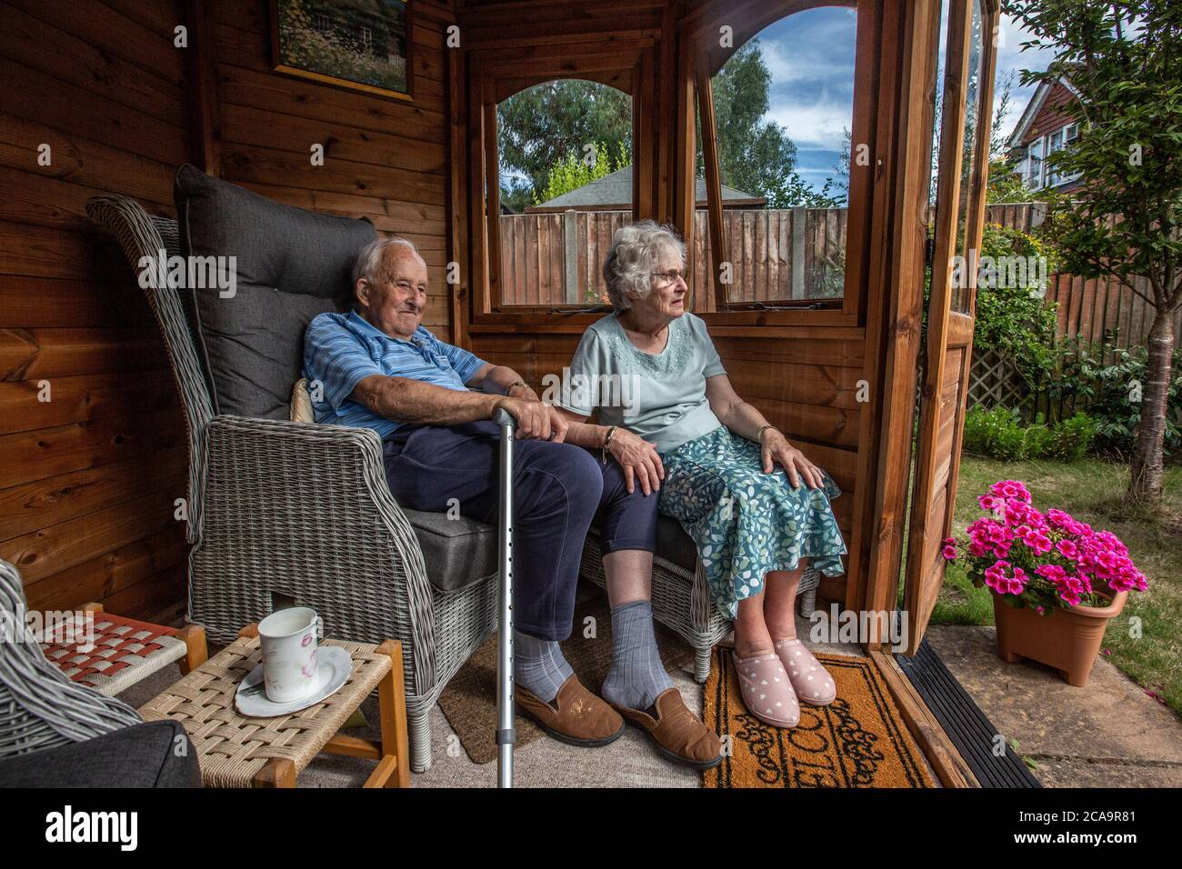 Coppie anziane negli anni 80 che si godono il caldo clima estivo nella loro casa estiva giardino, Inghilterra, Regno Unito Foto Stock