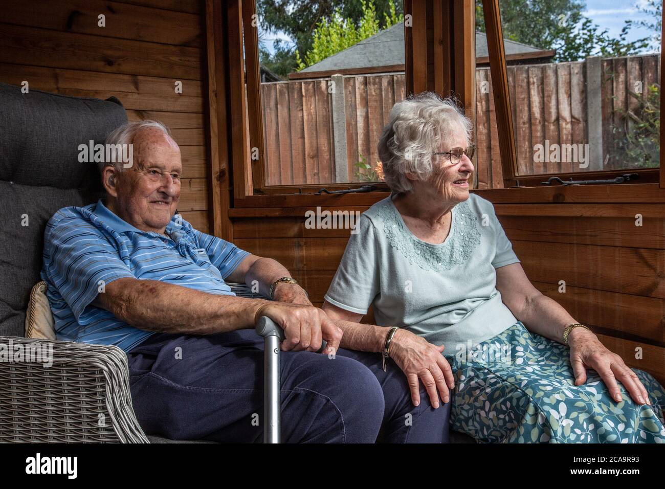 Coppie anziane negli anni 80 che si godono il caldo clima estivo nella loro casa estiva giardino, Inghilterra, Regno Unito Foto Stock