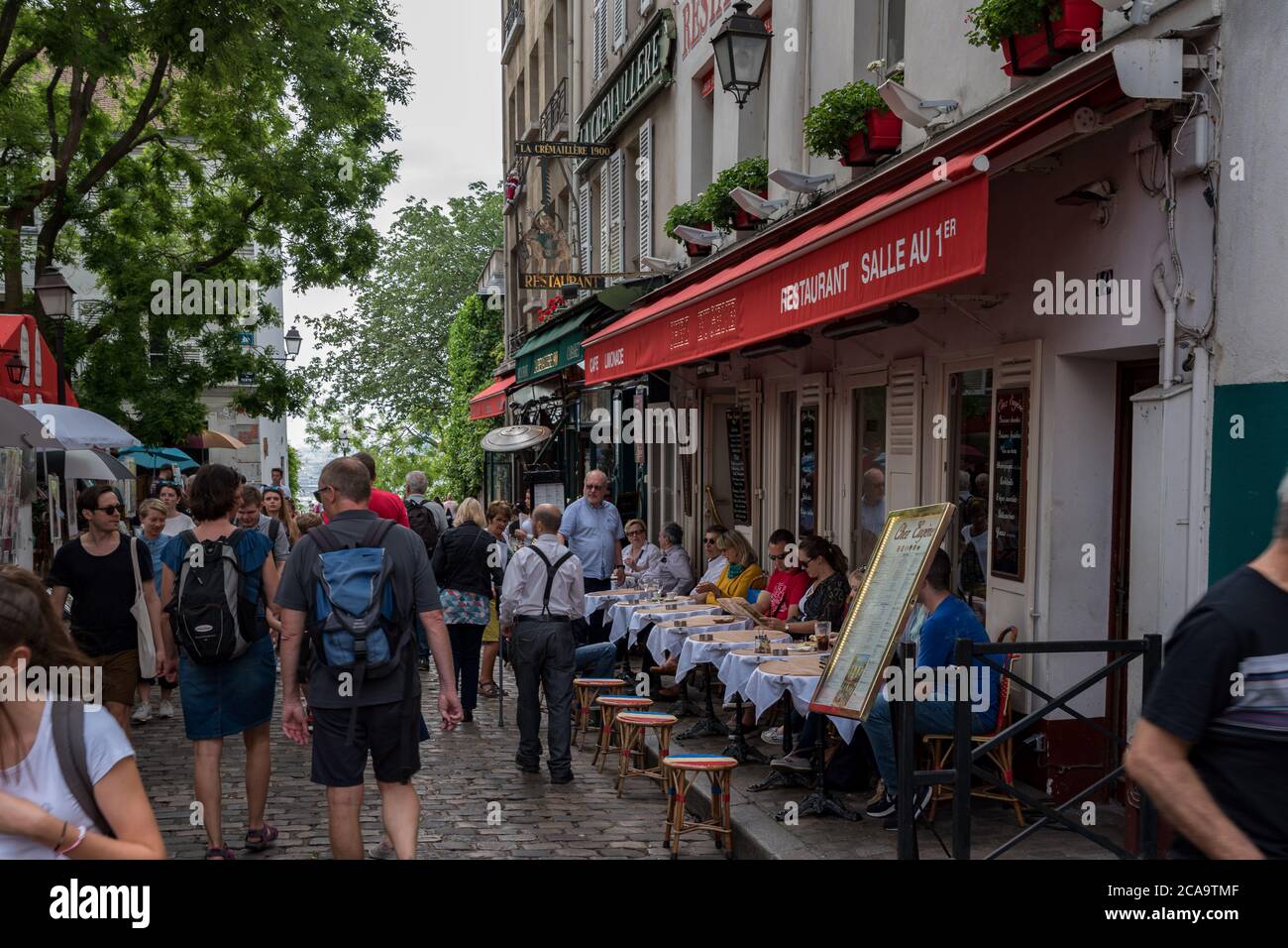 Turisti e visitatori seduti nei ristoranti intorno alla Place du Tertre e guardare i pittori. Foto Stock