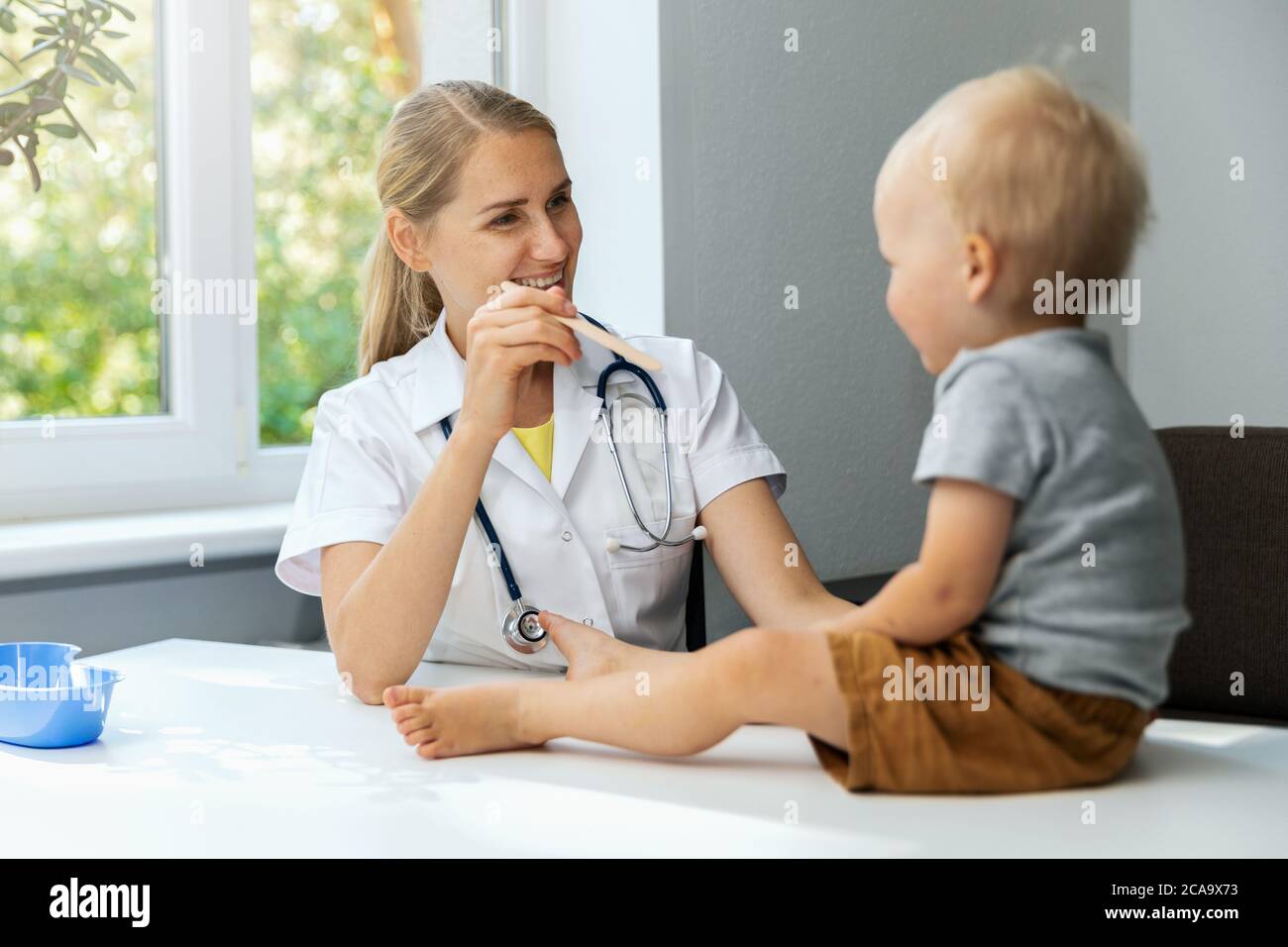 pediatra in ufficio che controlla la gola del bambino con bastone di legno Foto Stock