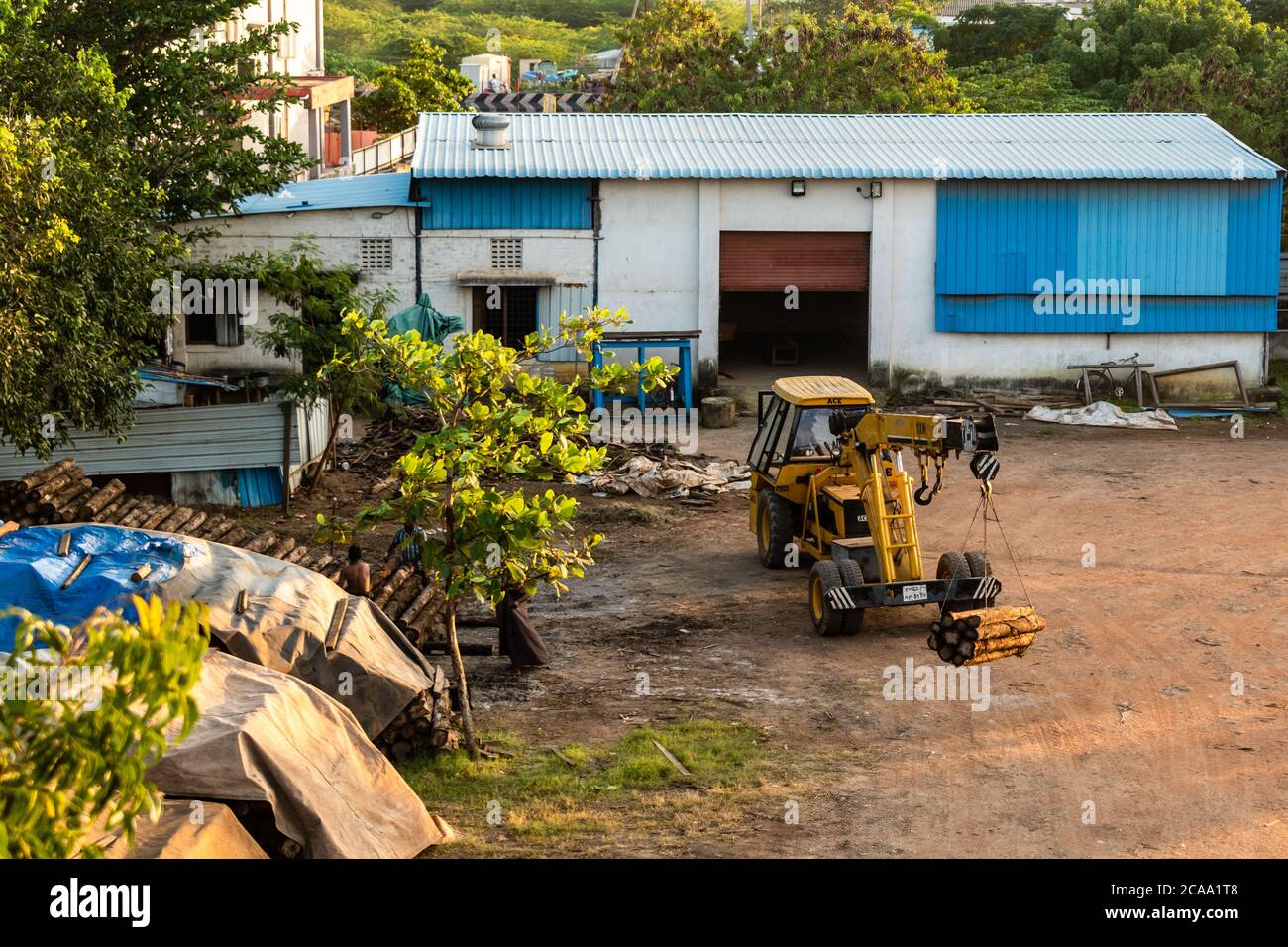 Chennai, Tamil Nadu, India - Gennaio 2020: Una gru JCB gialla che solleva tronchi di legno in un mulino per legno. Foto Stock