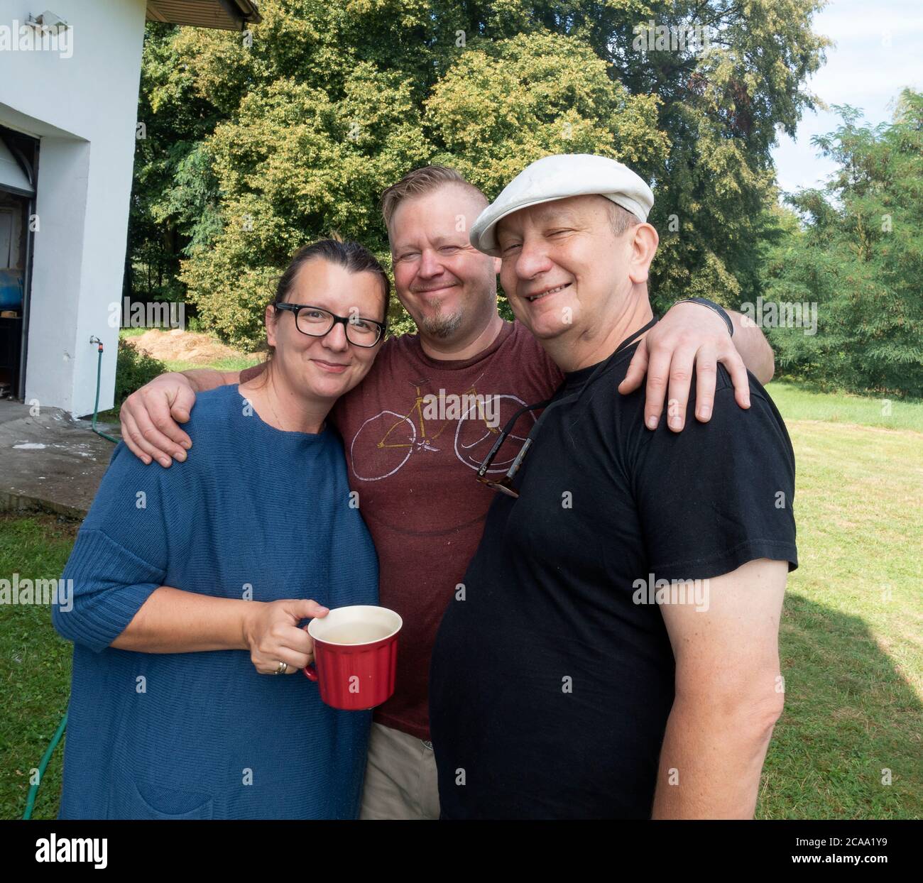 Amorevole padre polacco, figlia e genero con le braccia intorno a sé tenendo una tazza di caffè sorridente. Zawady Gmina Rzeczyca Polonia Foto Stock