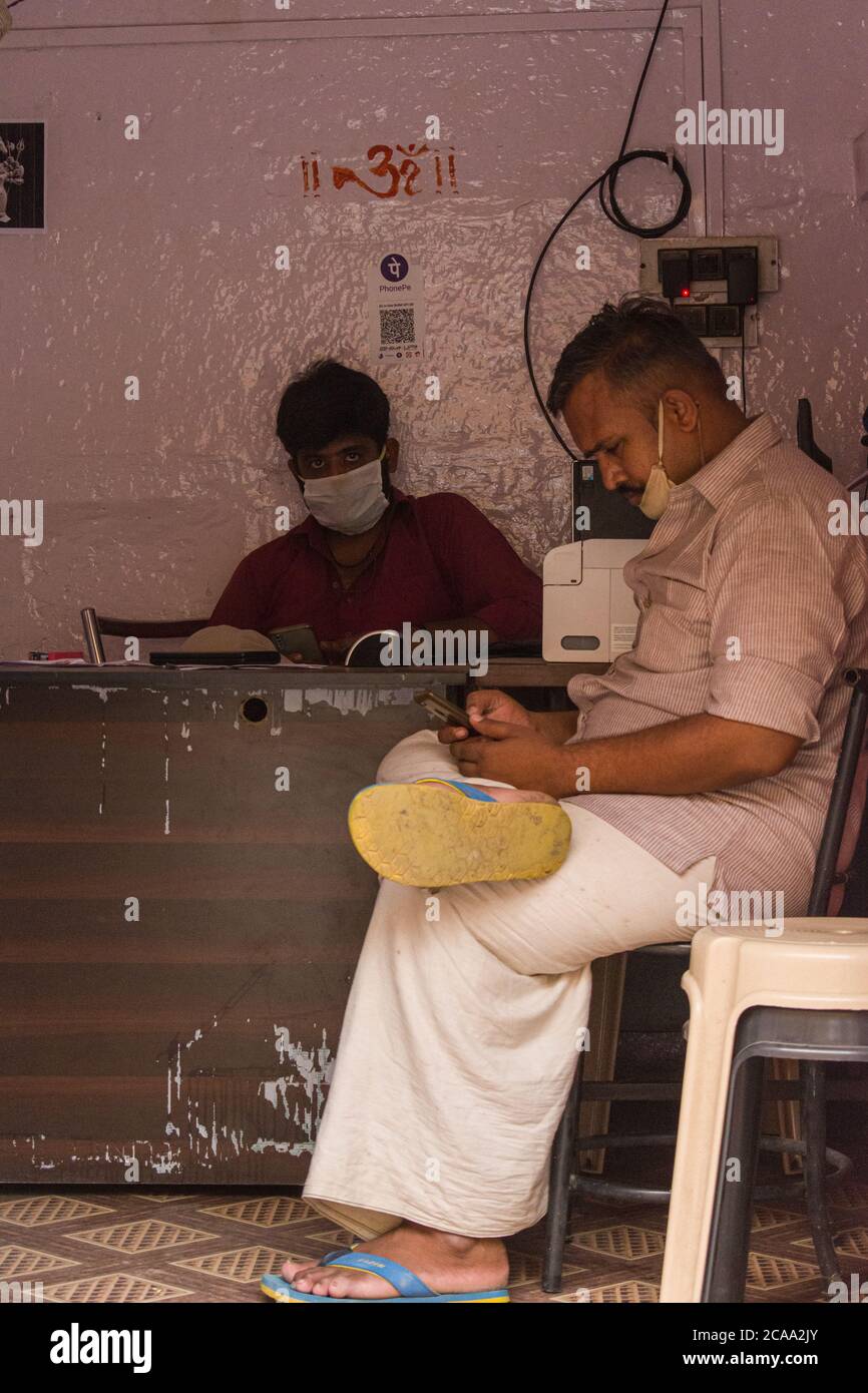 jaisalmer, rajasthan / India - Luglio 22 2020 : il cliente attende seduto su una sedia mentre un altro uomo completa il suo lavoro Foto Stock