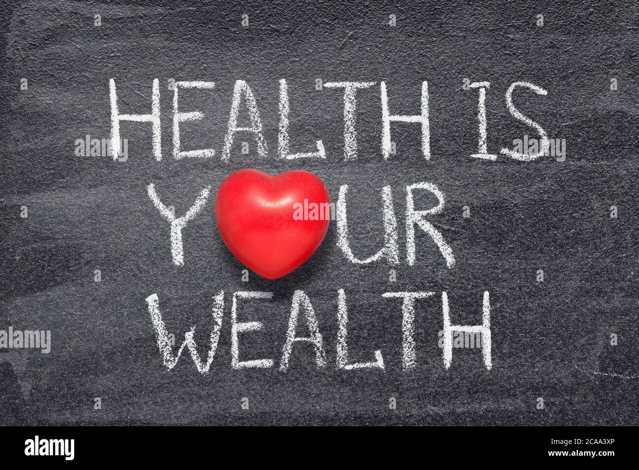la salute è la tua frase di ricchezza scritta sulla lavagna con il simbolo del cuore rosso Foto Stock