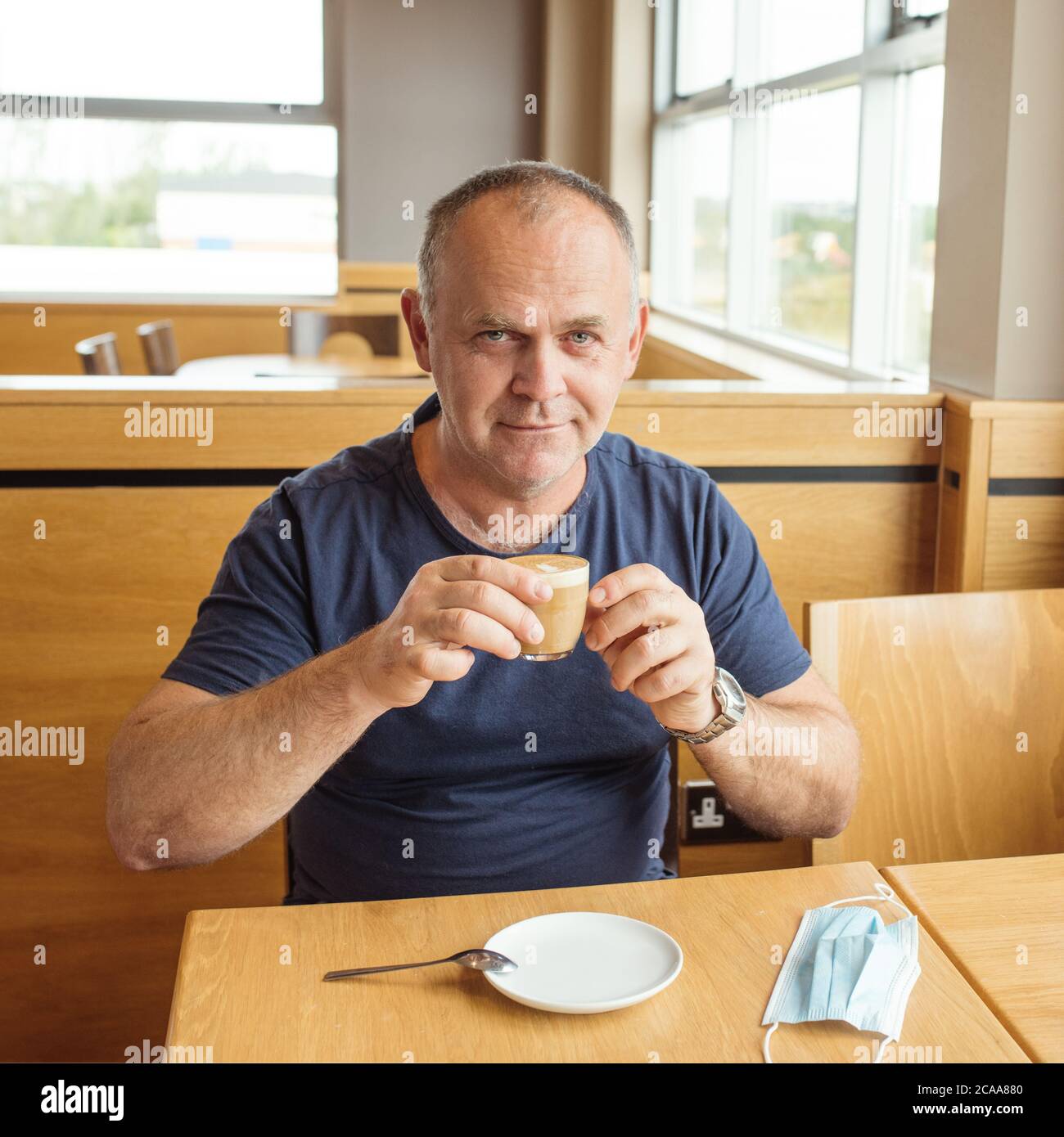 l'uomo ha tolto la maschera e sta bevendo caffè Foto Stock