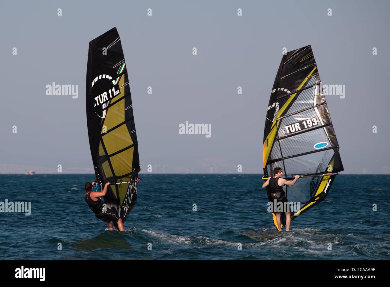 Windsurf / urla, TURCHIA - 9 luglio 2020: Un uomo da corsa che usa la vela  per spingere la sua tavola da surf . Le vele sono generalmente piene di  adesivi sponsor Foto stock - Alamy