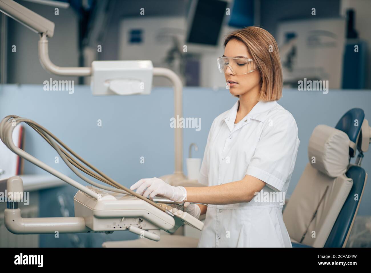 donna dentista seria concentrata sul lavoro, utilizzare attrezzature speciali per il trattamento dei denti, fornitore di assistenza sanitaria Foto Stock