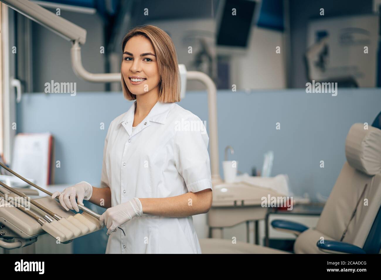 ritratto di dentista al lavoro, indossando l'uniforme bianca del medico, utilizzando strumenti e attrezzature mediche. Concetto di assistenza sanitaria Foto Stock