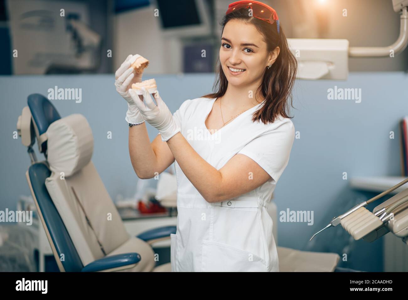 ritratto di dentista al lavoro, indossando l'uniforme bianca del medico, utilizzando strumenti e attrezzature mediche. Concetto di assistenza sanitaria Foto Stock