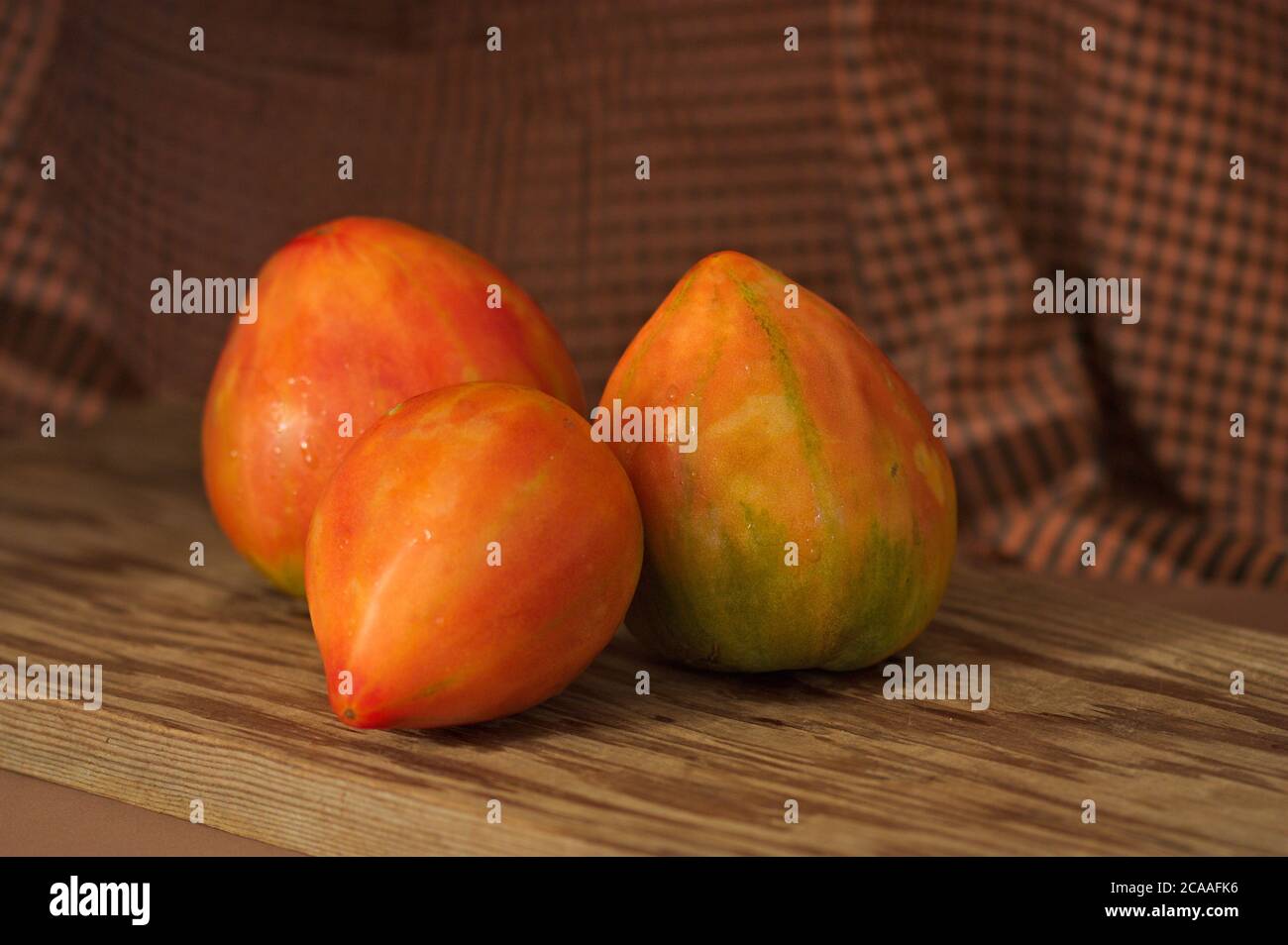 Ancora vita di pomodori rossi Valencia su una tavola di legno e scuri scacchi sfondo Foto Stock