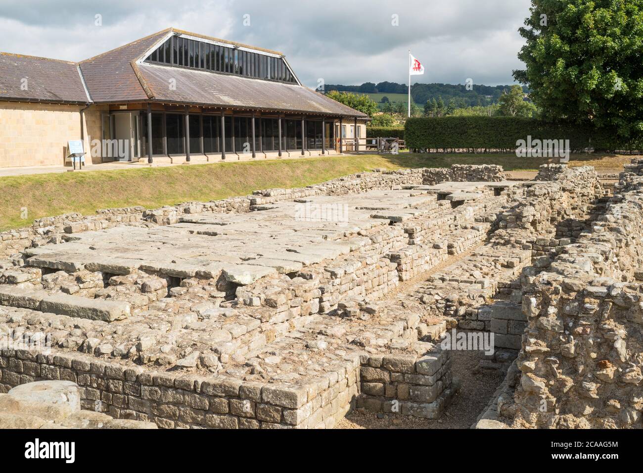 Resti del forte romano con l'edificio del museo dietro a Corbridge, Northumberland, Inghilterra, Regno Unito Foto Stock