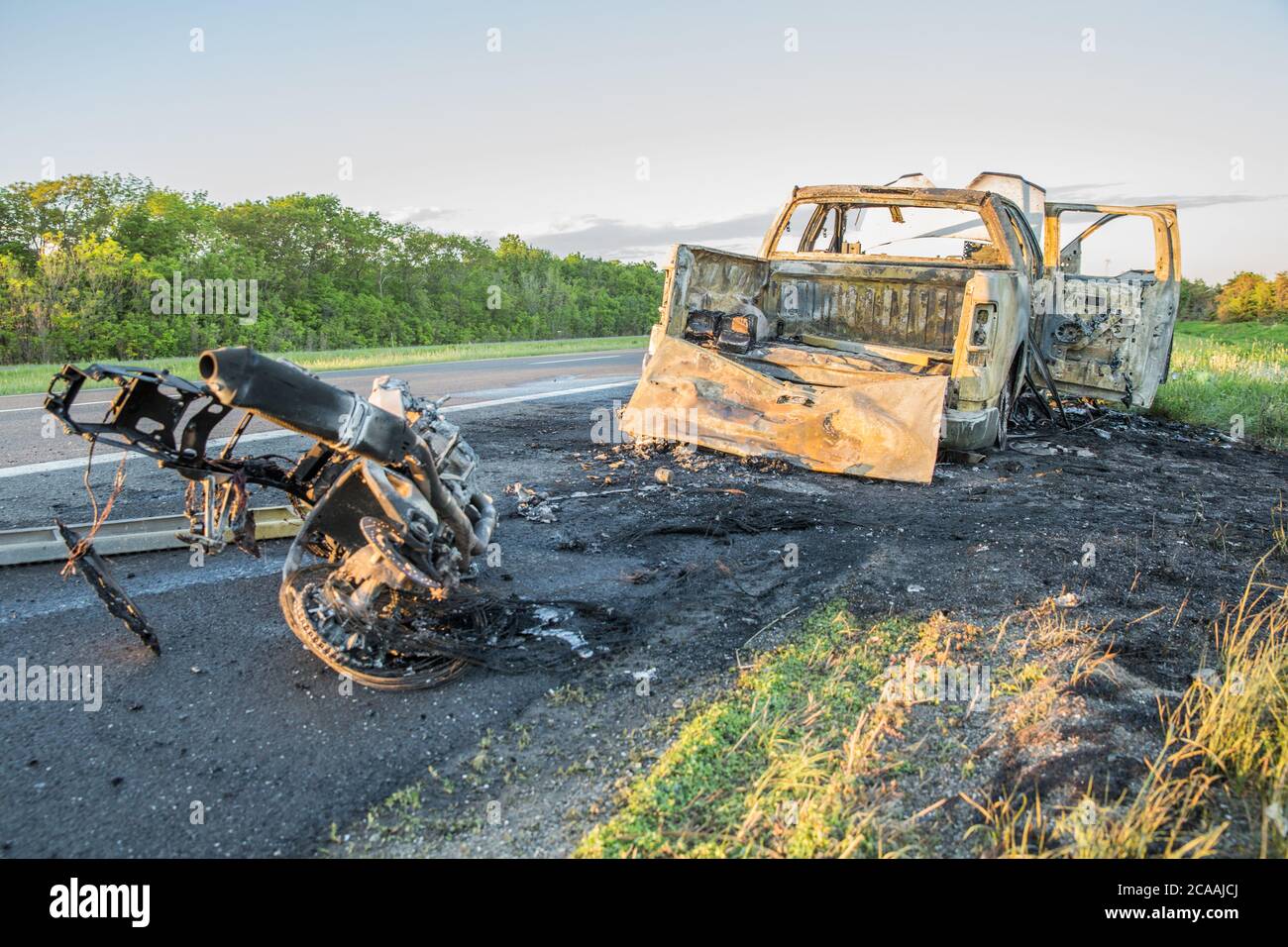 Moto e pick-up bruciati dopo incidente. Foto Stock