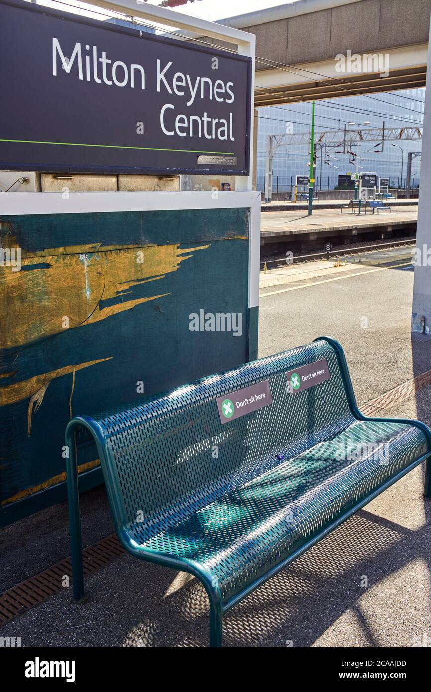 Non sedersi qui istruzioni sui posti a sedere piattaforma alla stazione ferroviaria di Milton Keynes durante le regole del Covid-19 Foto Stock