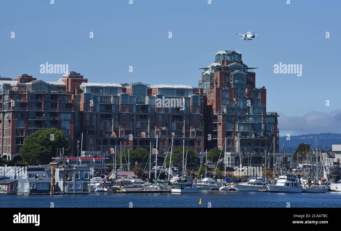 Victoria, British Columbia, Canada, 05 AGOSTO 2020 - UN aereo commerciale per passeggeri di Harbor Air scorre sopra l'edificio condominiale Shoal Point e le case galleggianti e le barche ormeggiate a Fisherman's Wharf dopo il decollo dal porto. Le compagnie aeree floatplane servono sia i mercati locali degli affari che i mercati turistici. Don Denton/Alamy Live News Foto Stock