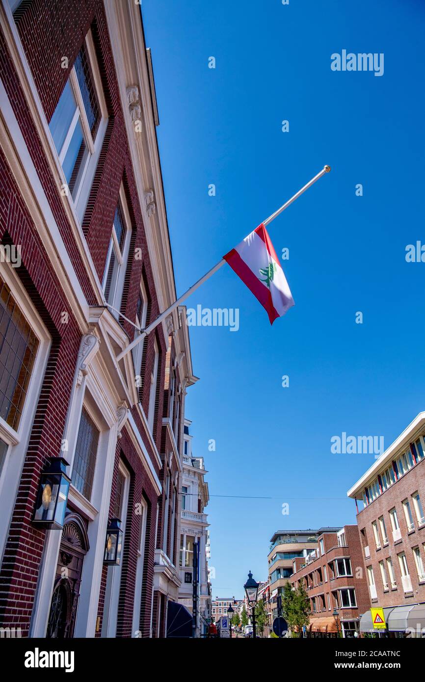La bandiera del Libano è appesa a metà palo all'ambasciata del Libano dell'Aia dopo una potente esplosione che ha attraversato la capitale del Libano; Il risultato dell'accensione di un enorme deposito di nitrato di ammonio nel porto principale della città.i soccorritori hanno cercato i sopravvissuti a Beirut dopo un'esplosione cataclismica nel porto ha seminato devastazioni in interi quartieri, uccidendo più di 100 persone, provocando migliaia di morti e gettando il Libano in una crisi più profonda. L'esplosione, che sembrava essere stata causata da un incendio che infiamma 2,750 tonnellate di nitrato di ammonio lasciato incustodito in un magazzino, è stata avvertita lontano quanto il CYP Foto Stock