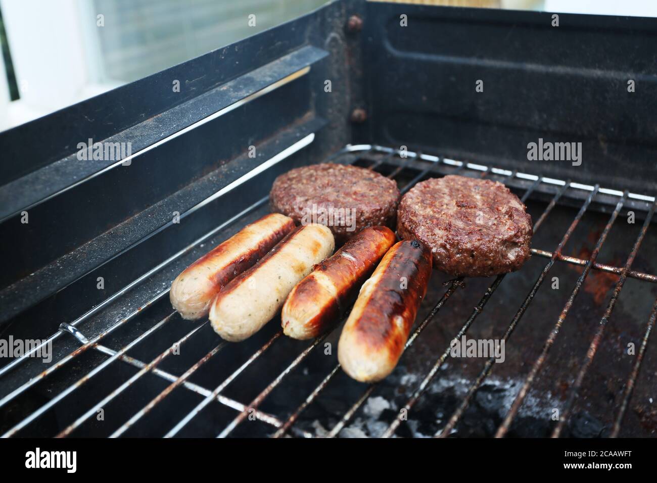 cucina all'aperto su un barbecue in estate salsicce di carbone e hamburger Foto Stock