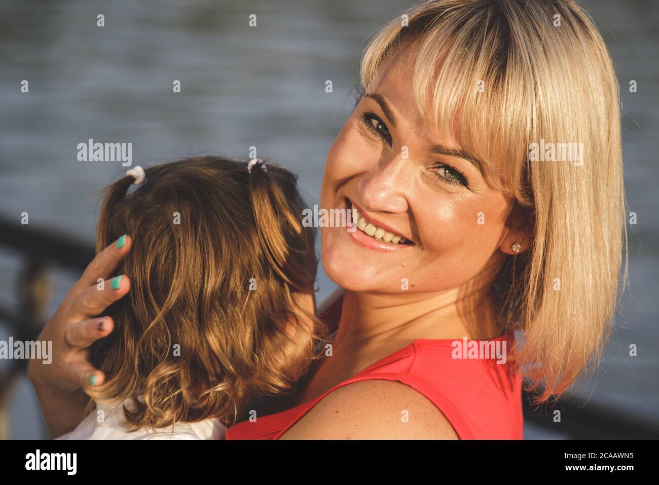 bella mamma bionda in una t-shirt rossa con sua figlia. primo piano Foto Stock