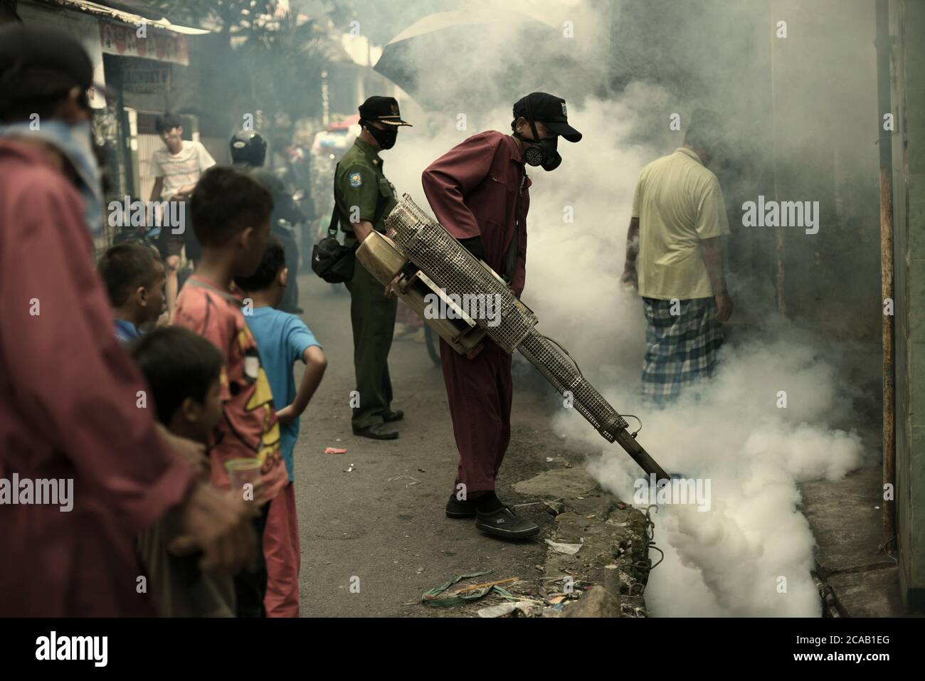 Ufficiali dell'ufficio sanitario locale che conducono una sessione di appannamento insetticida, una prevenzione dell'epidemia di febbre dengue in una densa zona popolata di Giacarta. Foto Stock