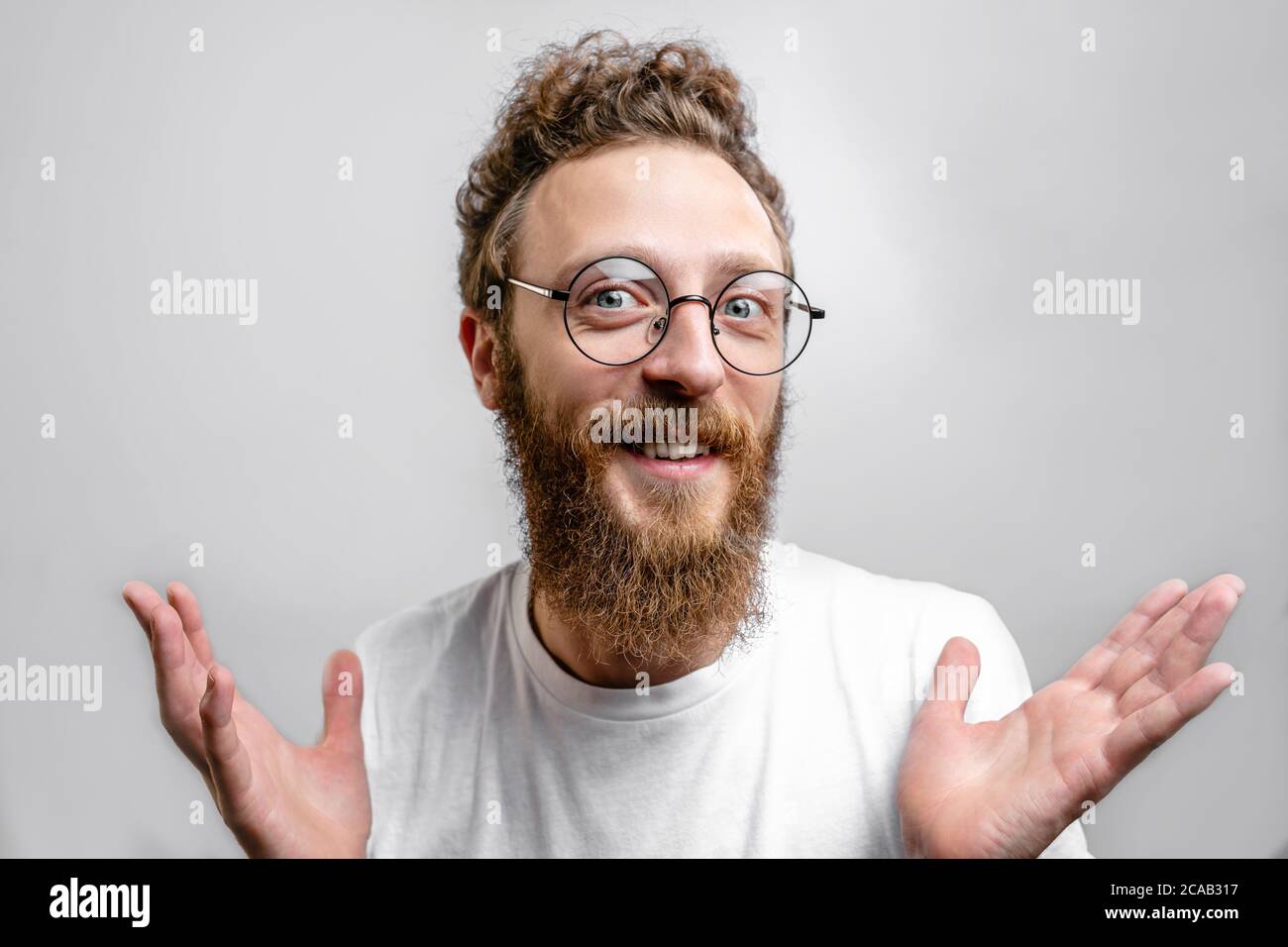 Uomo amichevole positivo che indossa occhiali guardando la macchina fotografica con dubbia, ottimista, domanda espressione. Foto Stock