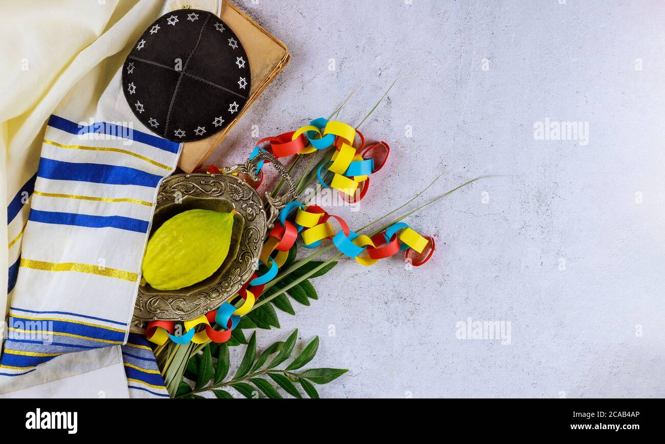L'etrog giallastro religioso ebreo del citron è usato durante la festa del kippah di Sukkot e del libro di preghiera del tallit Foto Stock