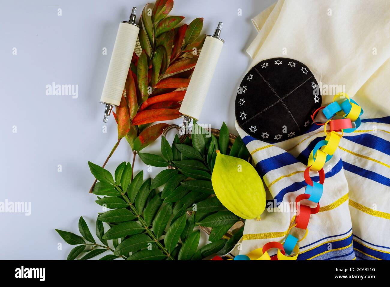 Etrog religioso giallo del citron, lulav della foglia con specie dalla festa ebraica di Sukkot su kippah e libro di preghiera parlata Foto Stock