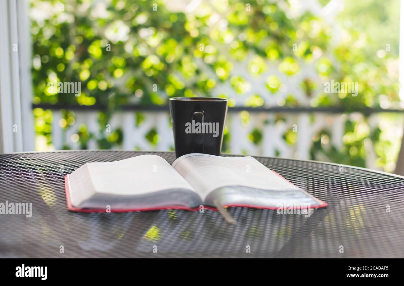 Una Bibbia o un libro su un tavolo con una tazza di tè. Foto Stock
