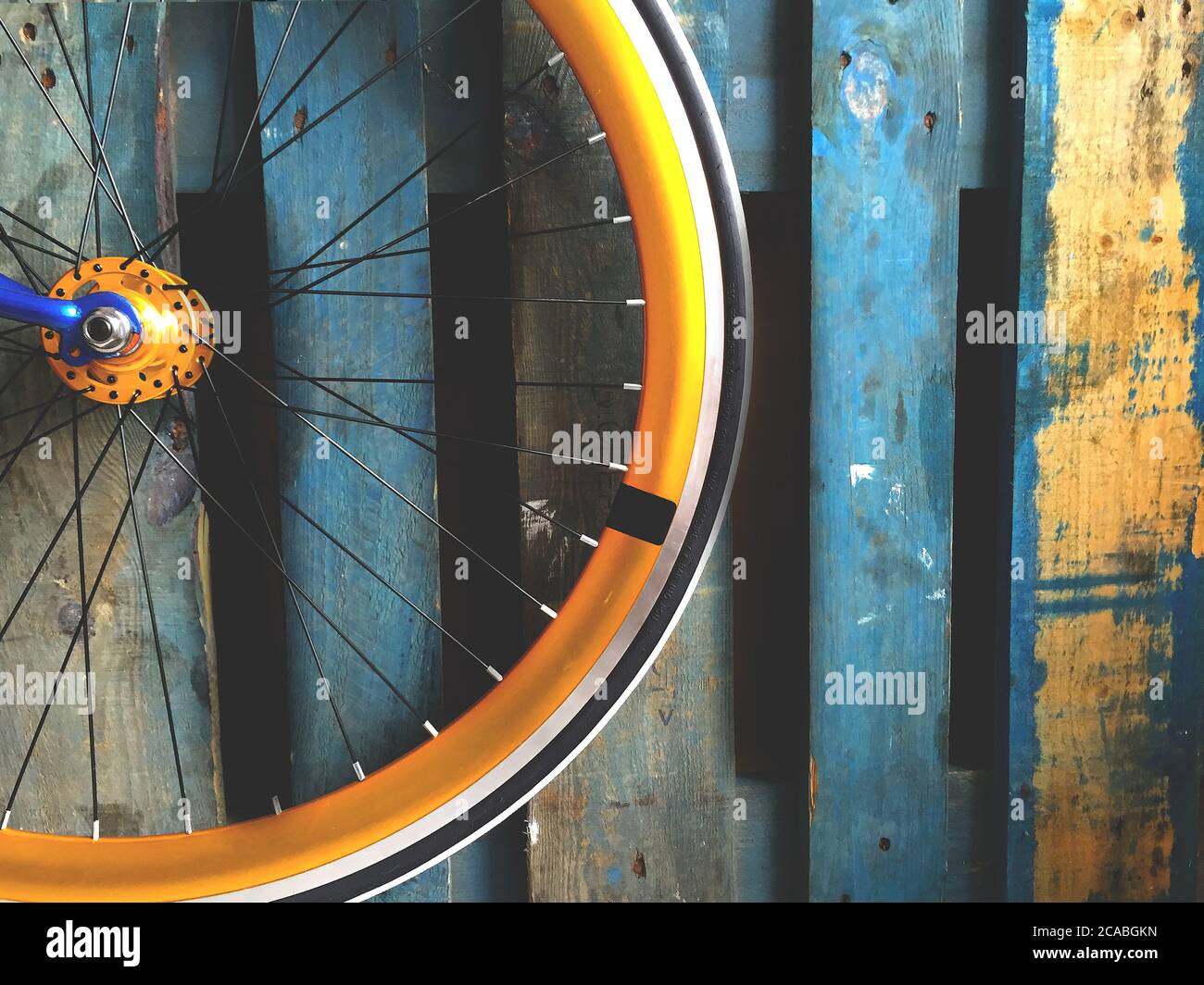 Primo piano della ruota di una bicicletta appoggiata una recinzione di legno blu Foto Stock