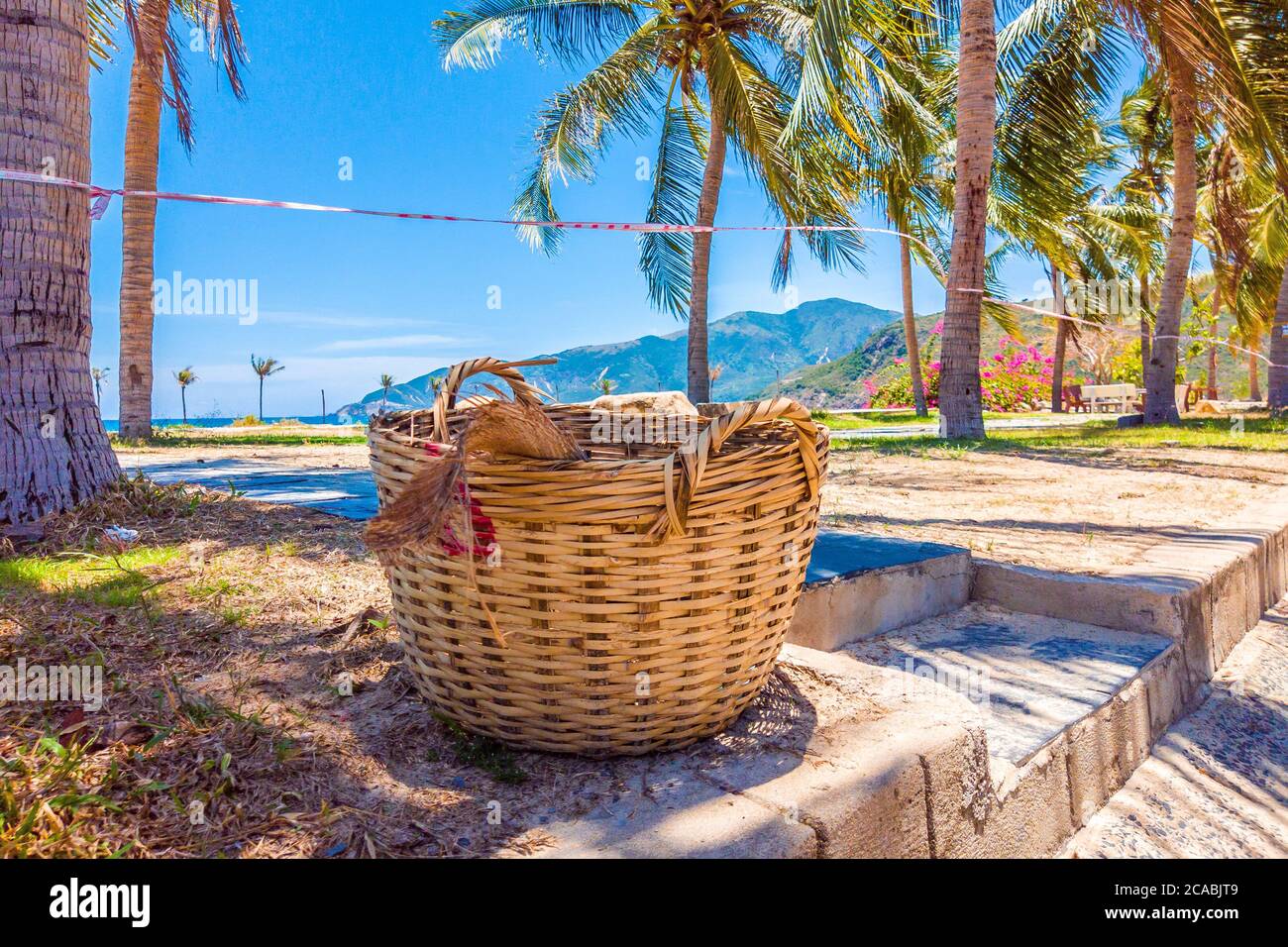 Quarantena nastro rosso e bianco attraverso l'esotica spiaggia bella con cielo blu chiaro. Concetto di vacanza, viaggio ritardato, niente più programmi estivi e casa Foto Stock
