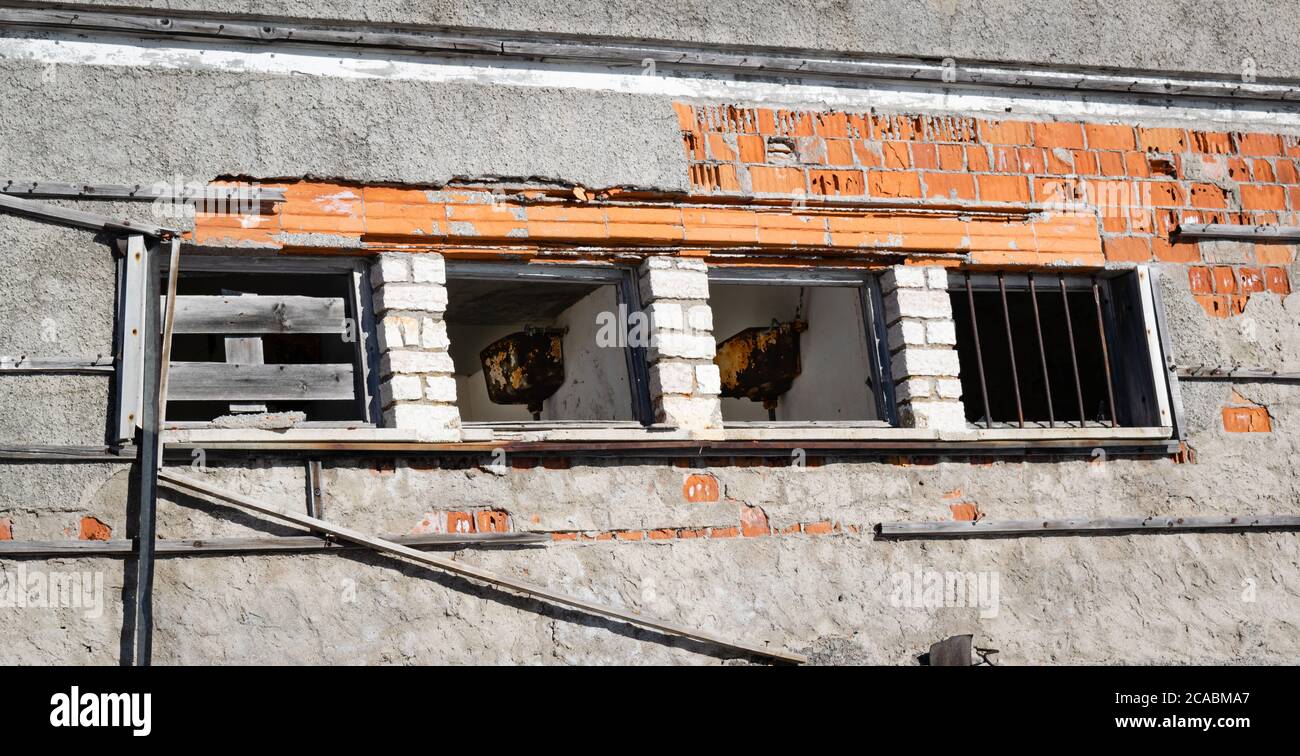 Parete esterna con fila di finestre distrutte. All'interno resti di bagno arrugginito. Edificio abbandonato situato a Monte Grappa (Veneto, Italia) Foto Stock
