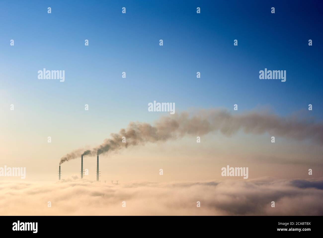 Cime di tre pile di fumo di centrale termica all'orizzonte preso dalla collina, tubi in nebbia mattutina su cielo blu, concetto di emissione pericolosa in atmosfera, generazione di energia, ecologia Foto Stock