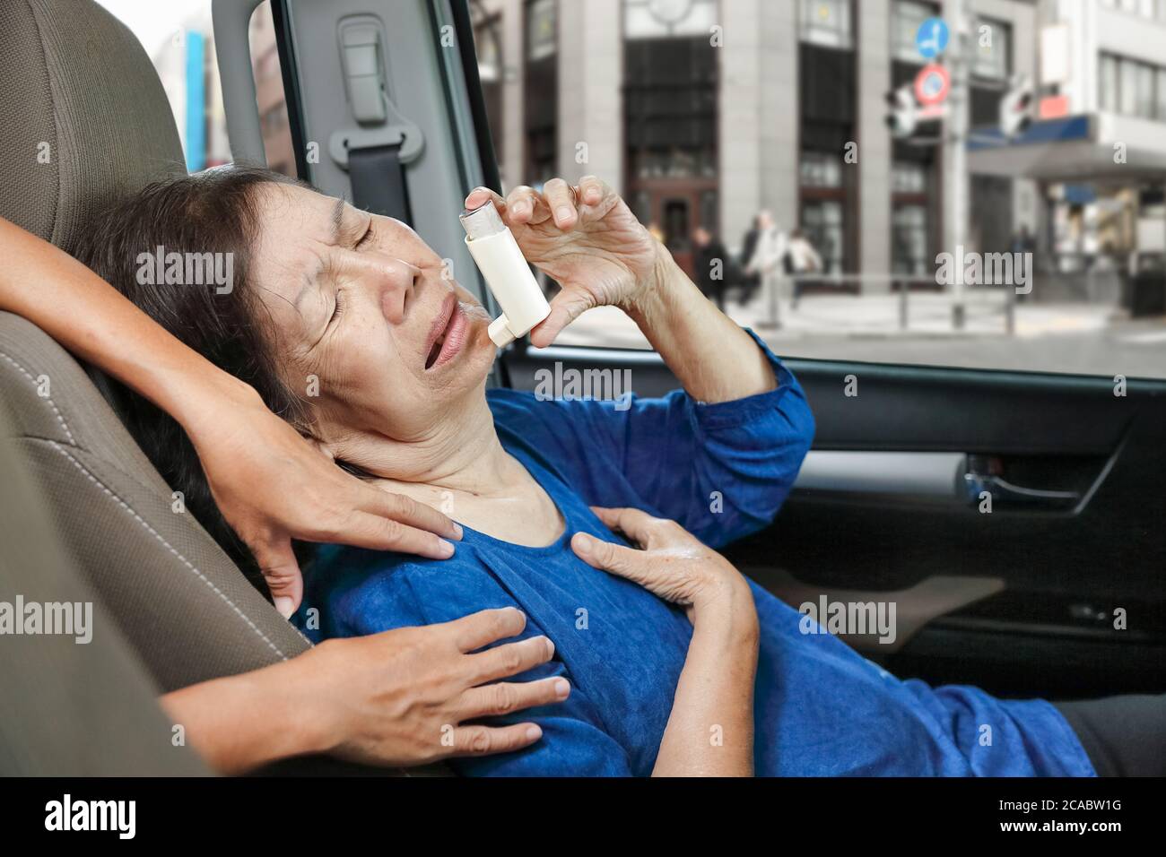 Donna anziana soffocante e che tiene uno spray per l'asma all'interno dell'auto sulla strada Foto Stock