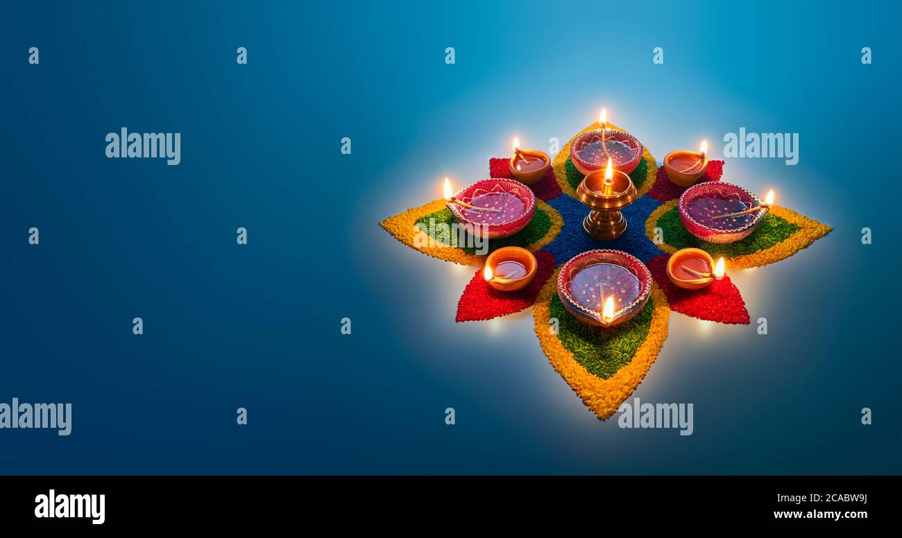 Happy Diwali, lampade diya accese su rangoli colorati Foto Stock