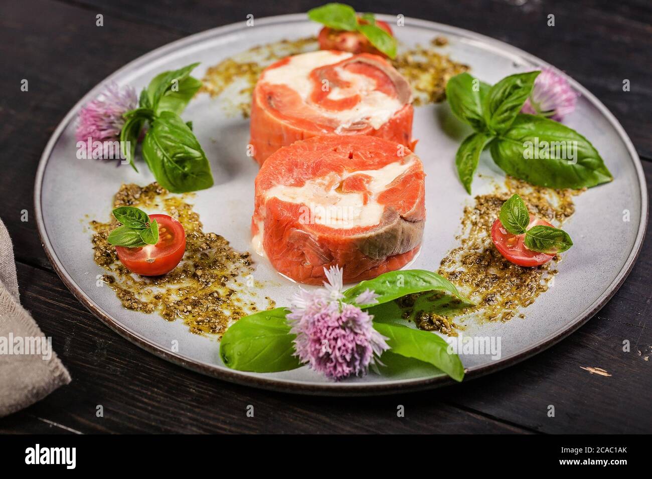 Appetitoso rotolo di salmone rosa con formaggio spalmabile e gamberi con salsa al pesto di ricotta e basilico fresco. Deliziosi piatti del ristorante di pesce Foto Stock