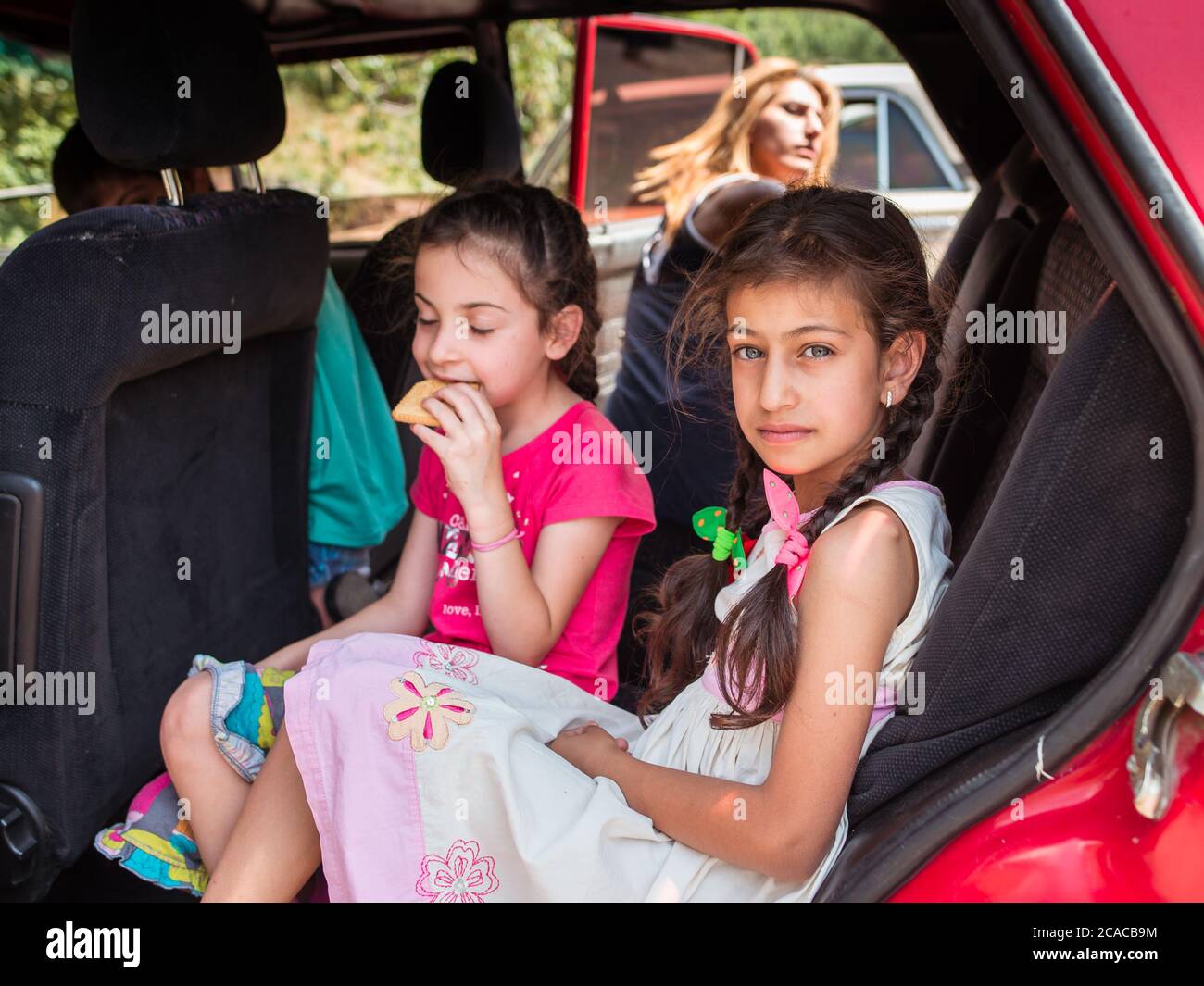 Monastero di Tatev / Armenia - 26 luglio 2019: Ritratto di bella ragazza armena con occhi chiari in auto rossa interni con la sua famiglia Foto Stock