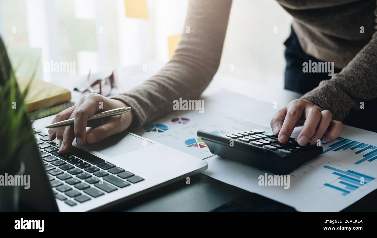 Donna d'affari che lavora in finanza e contabilità analizza il budget finanziario con la calcolatrice in ufficio Foto Stock
