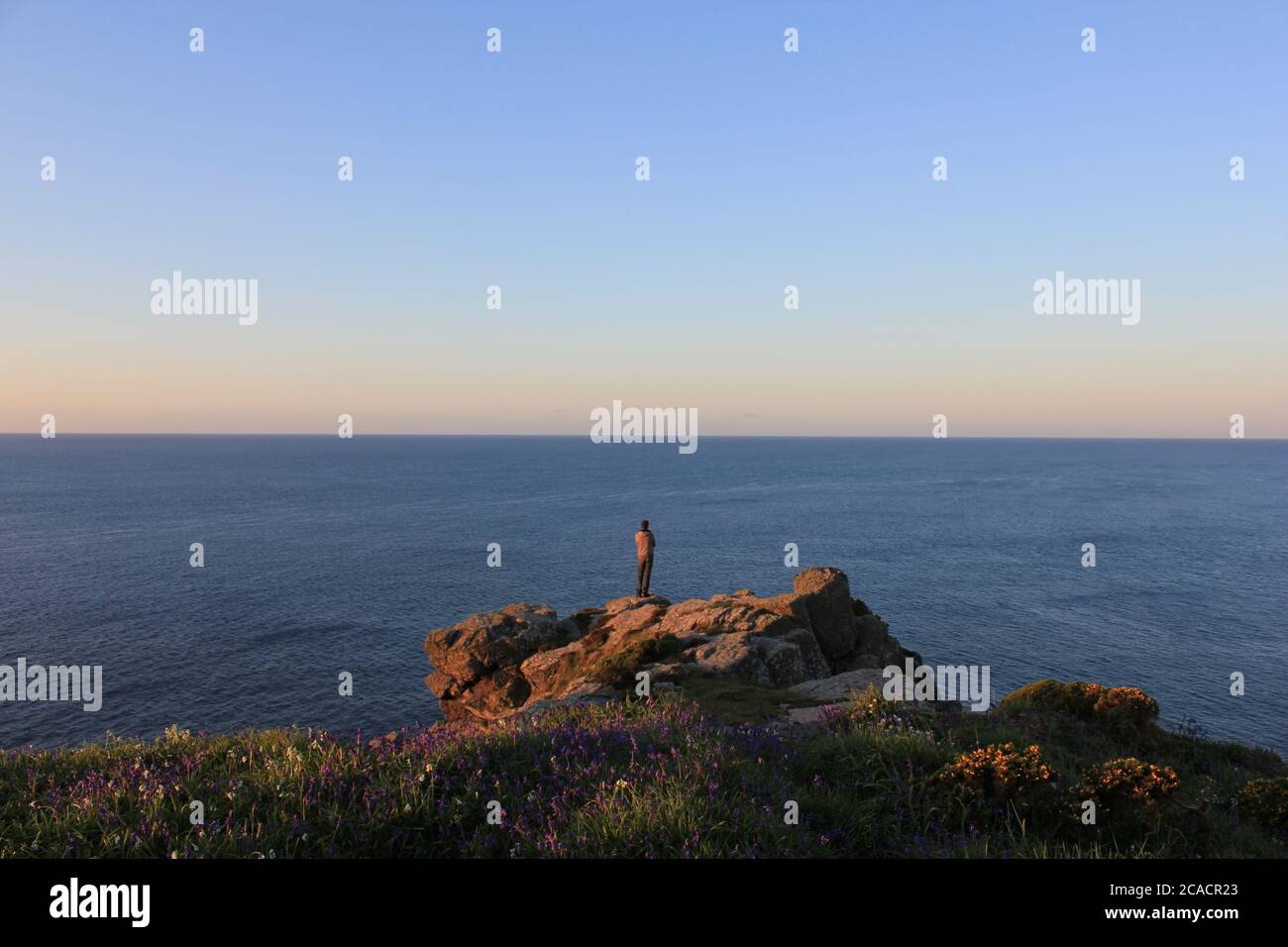 Figura in piedi su rocce costiere Foto Stock