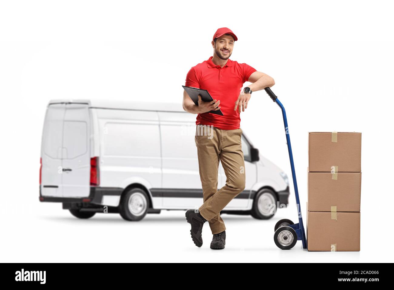 Ritratto a lunghezza intera di un addetto alla consegna con scatole di cartone sul camion a mano in piedi davanti ad un furgone bianco isolato su sfondo bianco Foto Stock