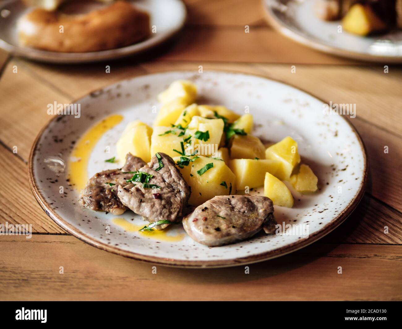 Fette di fagioli e patate bollite. Autentico shot di piatto con manzo arrosto o maiale e patate su un rustico tavolo in legno. Foto Stock